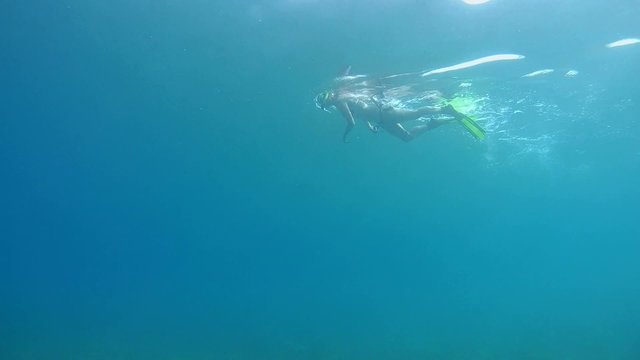 The woman floating on the surface of the blue water, snorkeling 