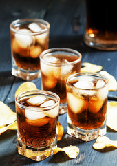 Cola with ice in glasses and chips, selective focus