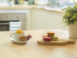 French macarons in cup and wooden tray on wooden table in a kitc