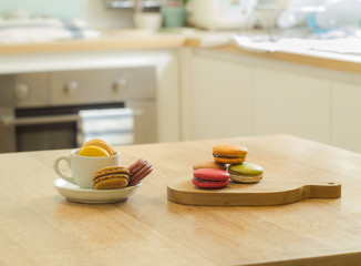 French macarons in cup and wooden tray on wooden table in a kitc