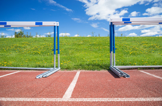 Hurdles stacked at the edge of athletics race track on a sunny day