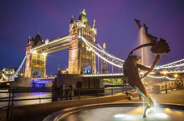Papier Peint photo Fontaine London, United Kingdom - The lady and the dolphin fountain with the iconic illuminated Tower Bridge at night