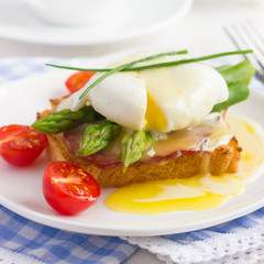 Fototapeta na wymiar Eggs Benedict with hollandaise sauce on toast with bacon and as