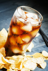Potato chips and cola in a large glass, selective focus