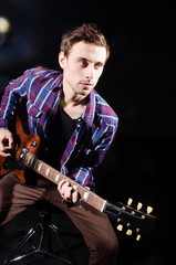 Obraz premium Man playing guitar in dark room