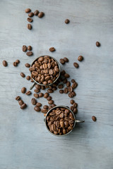 Coffee beans in silver vintage cups on wooden background
