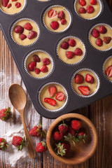 cooking muffins with fresh strawberries vertical top view
