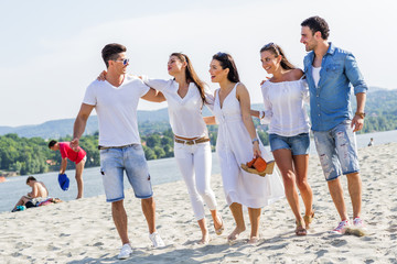 Obraz premium Group of young people holding hands on beach