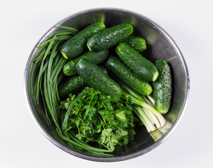 Fresh cucumbers and  herbs in a bowl isolated