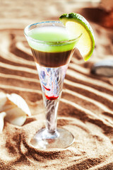 short cocktail on the sand with a drop of red hot, lemon, lime