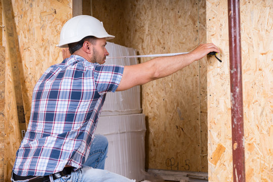 Construction Worker Measuring Width of Door Frame