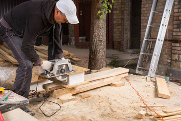 Man Using Power Saw to Cut Planks of Wood