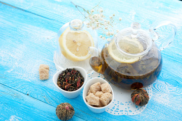 Ripe lemon, cinnamon and fruit drink in glass teapot on wooden