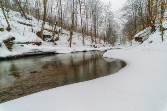 Winter river in the Carpathian Mountains with snow-covered banks