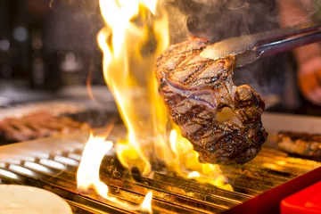 Papier Peint photo Lavable Steakhouse Steak sur un grill ouvert avec des flammes
