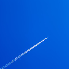 White contrail trace of plane on clear blue sky.