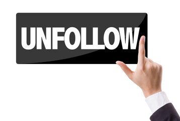 Businessman pressing button with the text: Unfollow