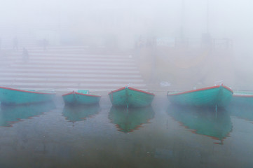 Boats on sacred river Ganges at cold foggy winter morning