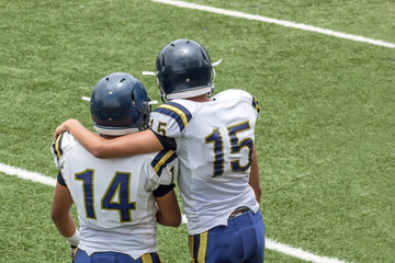 Fototapeta premium Kids standing back on a football field with black helmets and white jerseys 