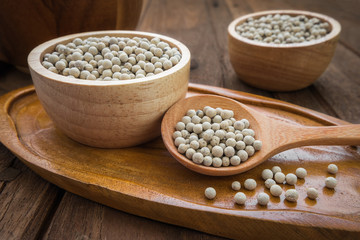 White pepper on wooden spoon and bowl
