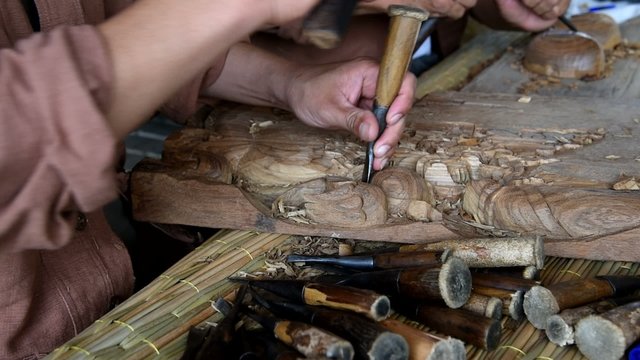 Hands of the craftsman wooden carving a bas-relief.