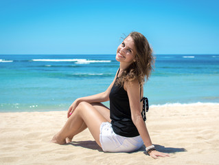 Fototapeta na wymiar Young woman sitting on the beach and relaxing 