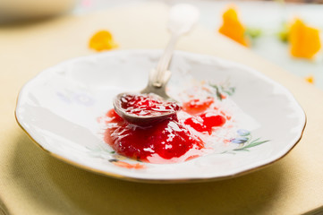 Red jam in plate with spoon, close up