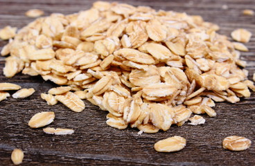 Heap of oat flakes on wooden background