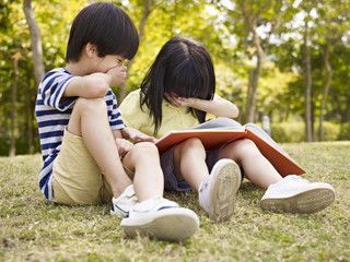 asian children reading book outdoors