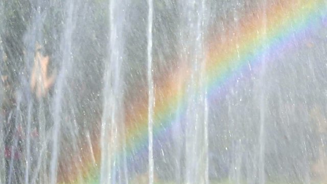 Real rainbow in urban fountain in park