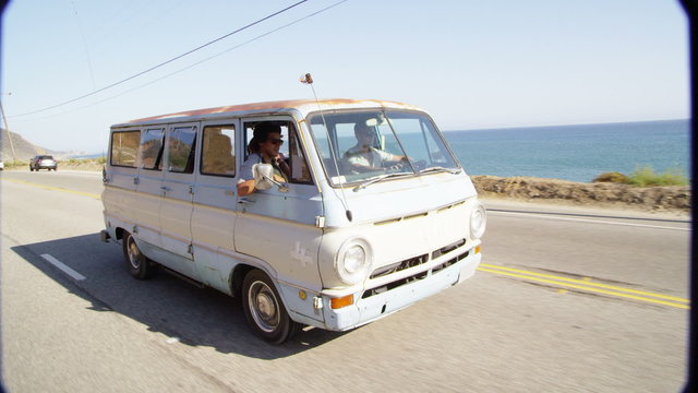 Group of young people on road trip driving old van