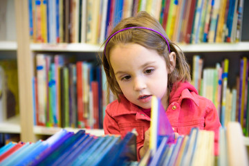Little girl is choosing a book in the library
