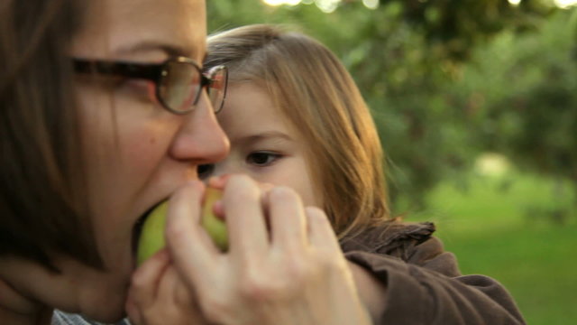Mother and young daughter share an apple