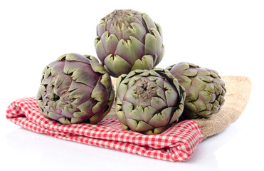 Obraz premium Fresh green purple artichokes on burlap