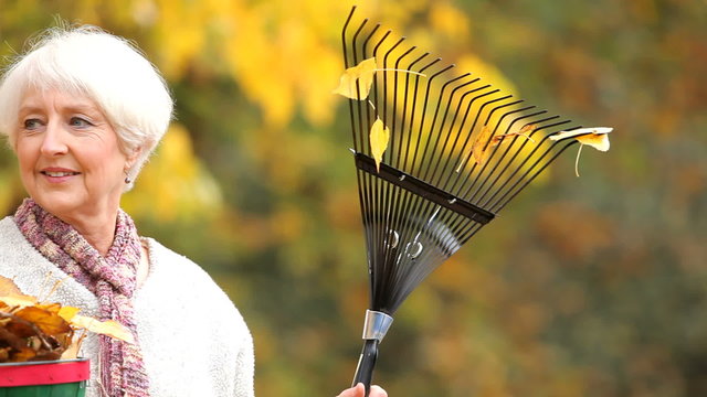 Fall portrait of senior woman with rake