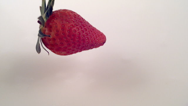 Strawberry splashing into milk, super slow motio