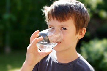 Little boy drink water in nature