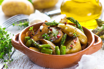 Delicious baked young potatoes in a cup on a wooden background
