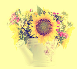 Fototapeta premium Yellow sunflowers and colored wild flowers in a white sprinkler