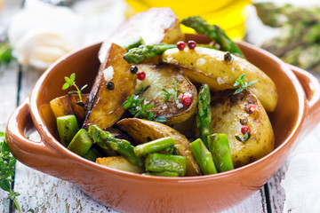Delicious baked young potatoes in a cup on a wooden background