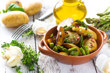 Delicious baked young potatoes in a cup on a wooden background