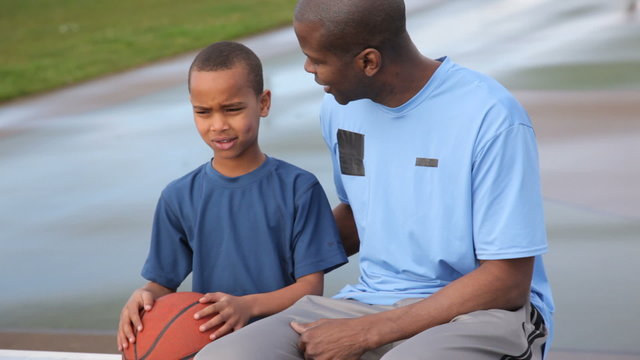Portrait of African American father and son with basketball  