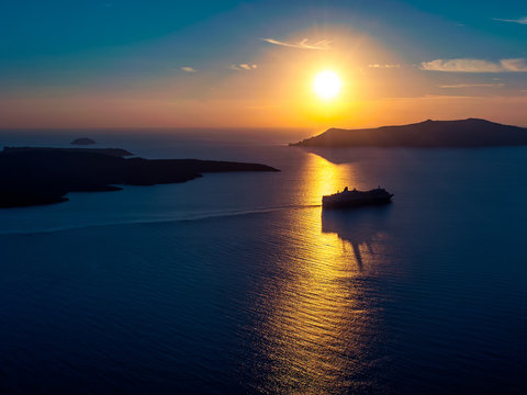 Cruise ship silhouette in sunset light with a few islands on background