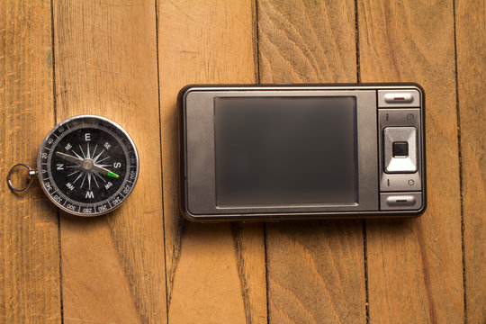 smartphone and compass on wooden background