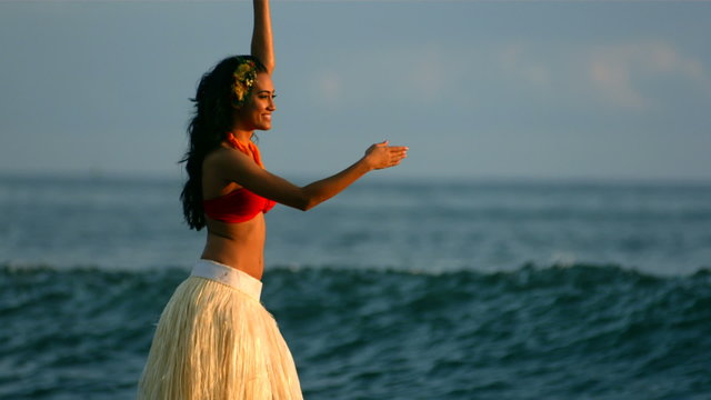 Hula dancer performs by ocean waves, slow motion