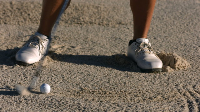 Golfer hits ball from sand trap