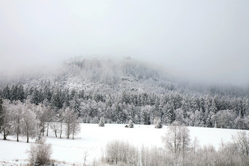Peak Szczeliniec Great in the clouds. Winter in Table Mountain National Park, Poland. Gloomy day.