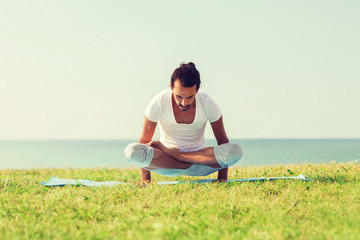 Naklejka na ściany i meble smiling man making yoga exercises outdoors