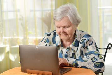 Senior woman with laptop in her room.