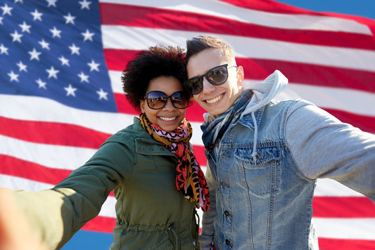 happy couple taking selfie over american flag